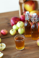 Image showing glass and bottles of apple juice on wooden table