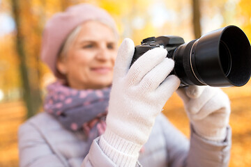 Image showing senior woman with photo camera at autumn park