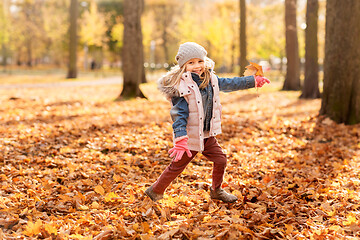 Image showing happy girl running with maple leaf at autumn park