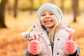 Image showing happy little girl at autumn park showing thumbs up