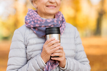 Image showing old woman with hot drink in tumbler at autumn park