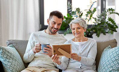 Image showing adult son and senior mother with photo at home