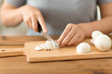 Image showing woman cutting champignons by knife on board