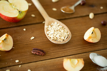 Image showing oatmeal in wooden spoon, cut apples and nuts
