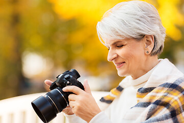 Image showing senior woman with photo camera at autumn park