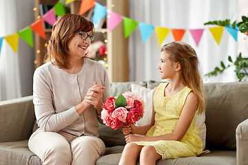 Image showing granddaughter giving grandmother flowers at home