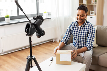 Image showing male video blogger opening parcel box at home