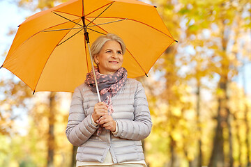 Image showing happy senior woman with umbrella at autumn park