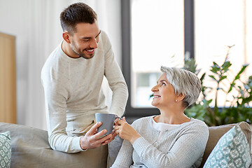 Image showing adult son bringing coffee to senior mother at home
