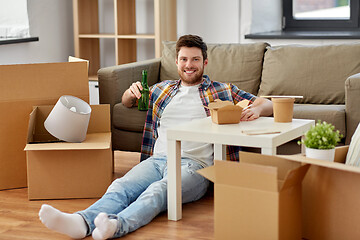 Image showing smiling man drinking beer and eating at new home