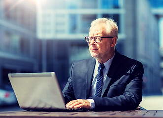 Image showing senior businessman with laptop at city street cafe