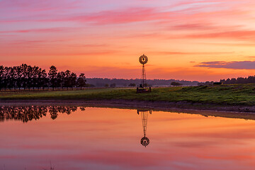 Image showing Windmill sits on farm land with beautiful sunrise sky