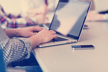 Image showing close up of business man hands typing on laptop with team on mee