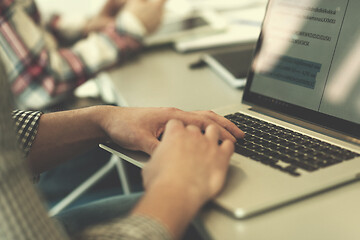 Image showing close up of business man hands typing on laptop with team on mee