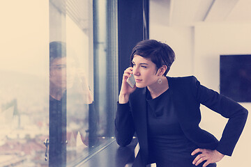 Image showing Elegant Woman Using Mobile Phone by window in office building