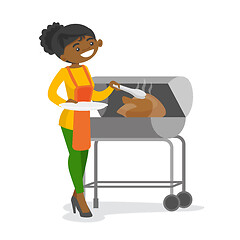Image showing African woman cooking chicken on the barbecue.
