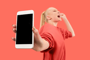 Image showing Portrait of a confident casual girl showing blank screen mobile phone isolated over coral background