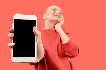 Image showing Portrait of a confident casual girl showing blank screen mobile phone isolated over coral background