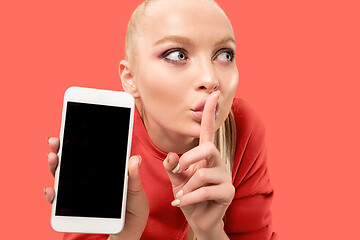 Image showing Portrait of a confident casual girl showing blank screen mobile phone isolated over coral background