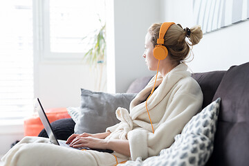 Image showing Stay at home and social distancing. Woman in her casual home bathrobe working remotly from her living room. Video chatting using social media with friend, family, business clients or partners