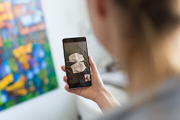 Image showing Stay at home, social distancing lifestyle. Woman at home using social media on phone to learn about the use of masks and preventative measures during corona virus pandemic.