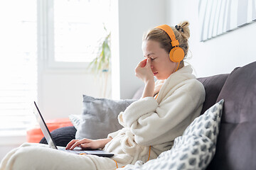 Image showing Stressed business woman in her casual home bathrobe working remotly from her living room during corona virus pandemic crisis. Stay at home and social distancing