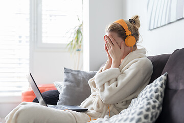 Image showing Stressed business woman in her casual home bathrobe working remotly from her living room during corona virus pandemic crisis. Stay at home and social distancing