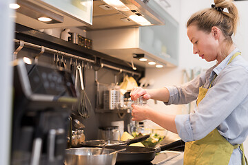 Image showing Stay at home and social distancing. Woman in her casual home clothing working remotly from kitchen dining table. Video chatting using social media with friend, family, business clients or partners