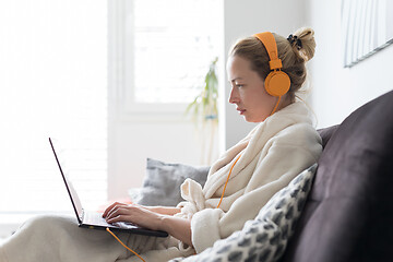 Image showing Stay at home and social distancing. Woman in her casual home bathrobe working remotly from her living room. Video chatting using social media with friend, family, business clients or partners