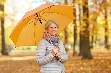 Image showing happy senior woman with umbrella at autumn park