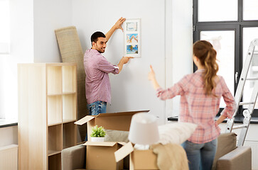 Image showing happy couple moving to new home and hanging photo