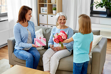 Image showing granddaughter giving flowers to grandmother