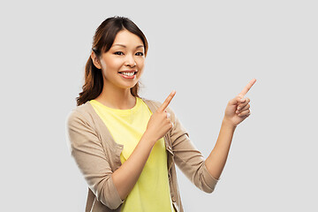 Image showing happy asian woman pointing fingers up