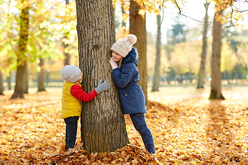 Image showing happy children at tree trunk in autumn park