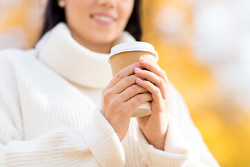 Image showing happy young woman drinking coffee in autumn park