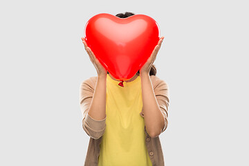 Image showing woman with face behind red heart shaped balloon