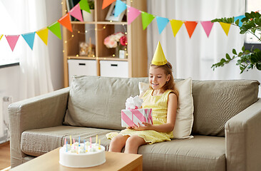 Image showing happy girl in party hat with birthday gift at home