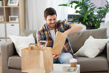 Image showing smiling man unpacking takeaway food at home