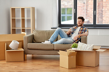 Image showing man with boxes and drinking coffee at new home