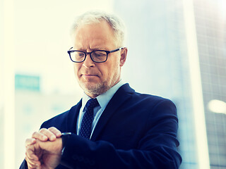 Image showing senior businessman checking time on his wristwatch