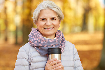 Image showing old woman with hot drink in tumbler at autumn park