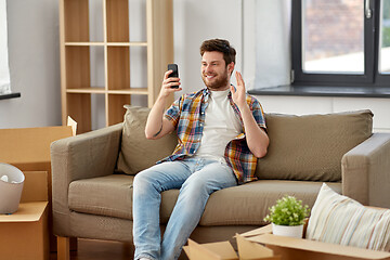 Image showing man with smartphone having video call at new home