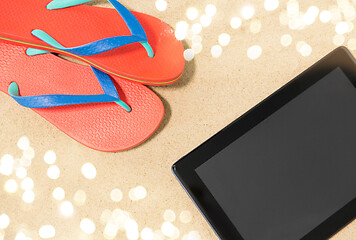 Image showing tablet computer and flip flops on beach sand