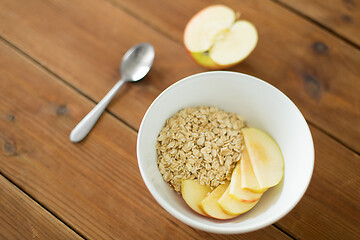 Image showing oatmeal in bowl with apple and spoon on table