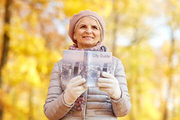 Image showing senior woman with city guide at autumn park