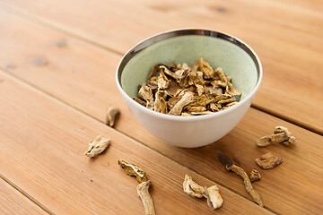 Image showing dried mushrooms in bowl on wooden background