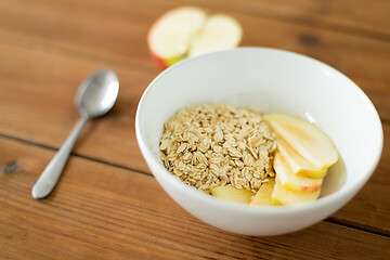 Image showing oatmeal in bowl with apple and spoon on table