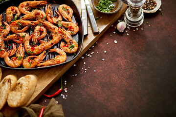 Image showing Grilled prawns in cast iron grilling pan with fresh lemon, parsley, chili, garlic white wine sauce