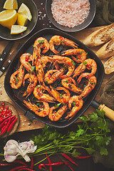 Image showing Tasty appetizing roasted shrimps prawns with spices on pan with ingredients on rusty background