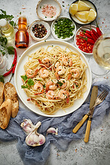 Image showing Spaghetti with shrimps on white ceramic plate and served with glass of white wine
